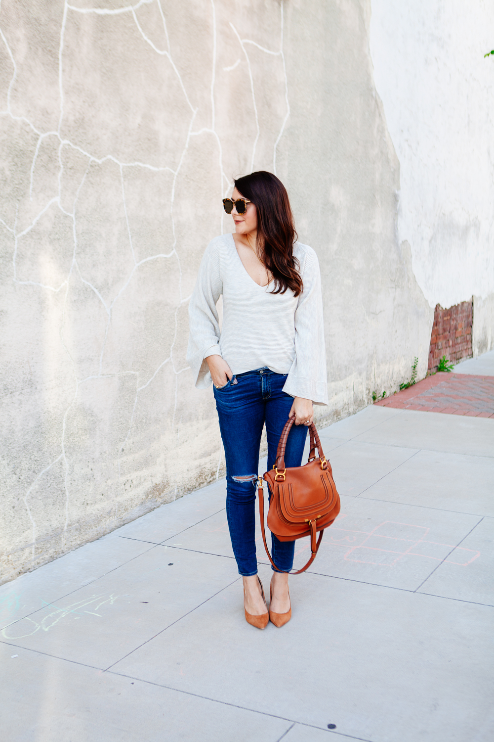 Bell sleeve sweater with skinny jeans and cognac accessories.